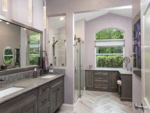 Large bathroom with two sinks, a shower, and purple walls.